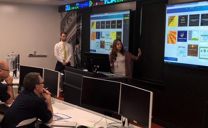 Photo of students giving a presentation in front of large screens